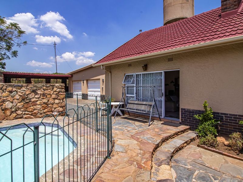 Outdoor pool area featuring a stone-paved patio, metal safety fencing, and direct access to the home via a sliding glass door.