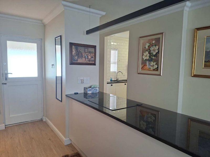 Open plan living area featuring a sleek granite breakfast bar, crown molding, and a view into the adjacent kitchen with subway tile backsplash.