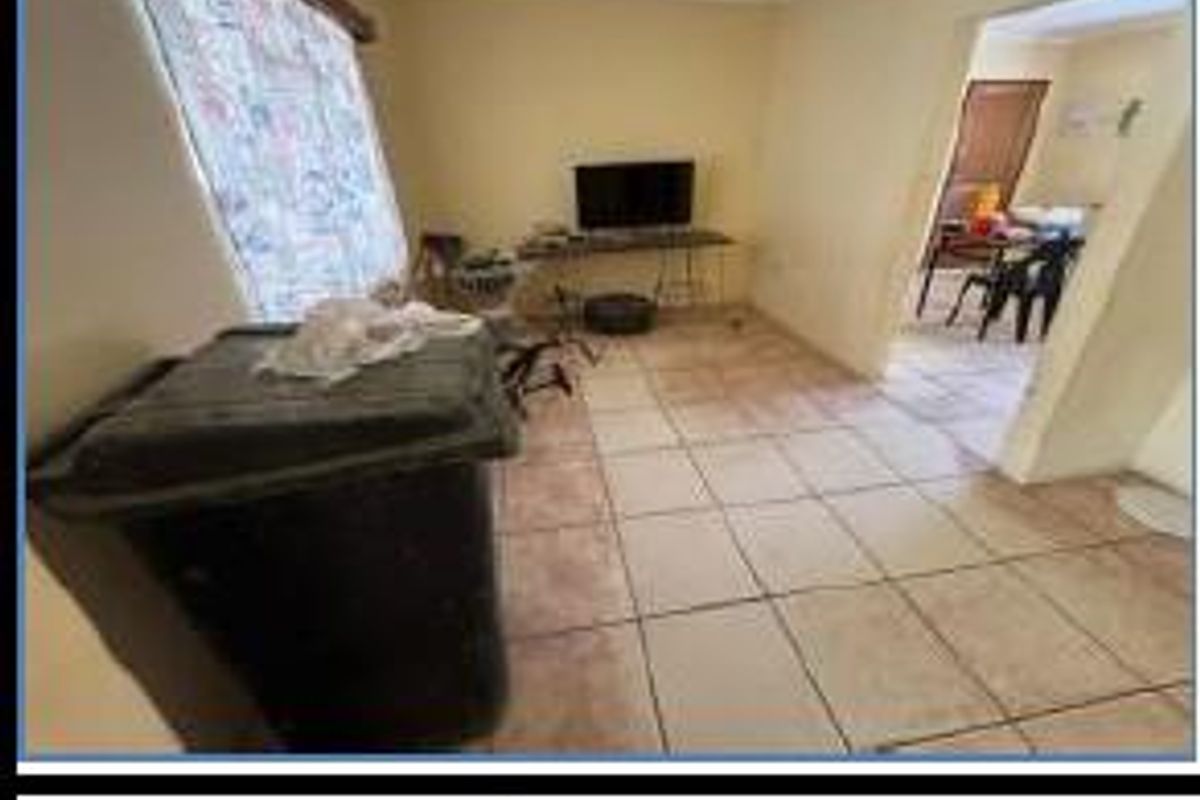 A living room area featuring tiled flooring and access to an adjacent room, providing a functional space for relaxation.