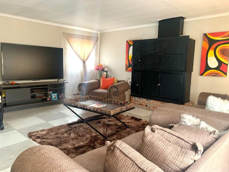 A comfortable living room featuring a prominent built-in fireplace and neutral tiled flooring, offering a functional space for relaxation.