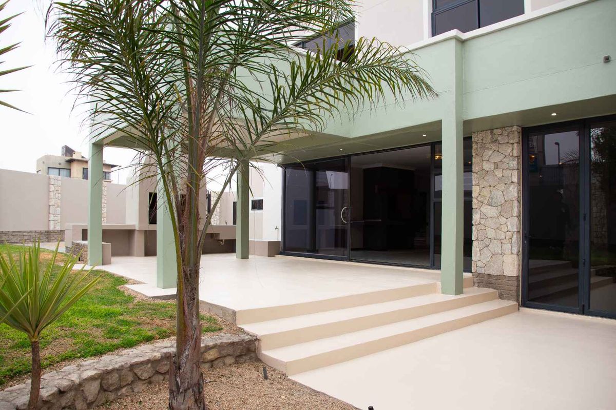 A modern covered patio featuring stone cladding, concrete steps, and large sliding glass doors leading into the home.