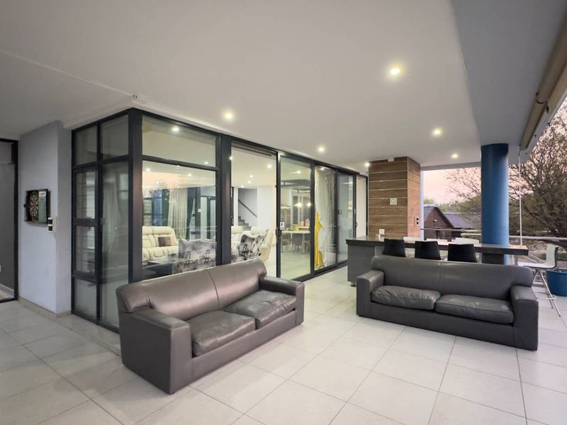 Spacious covered patio featuring tiled flooring, recessed lighting, and a built-in bar counter, seamlessly connecting to the interior living areas through large glass sliding doors.