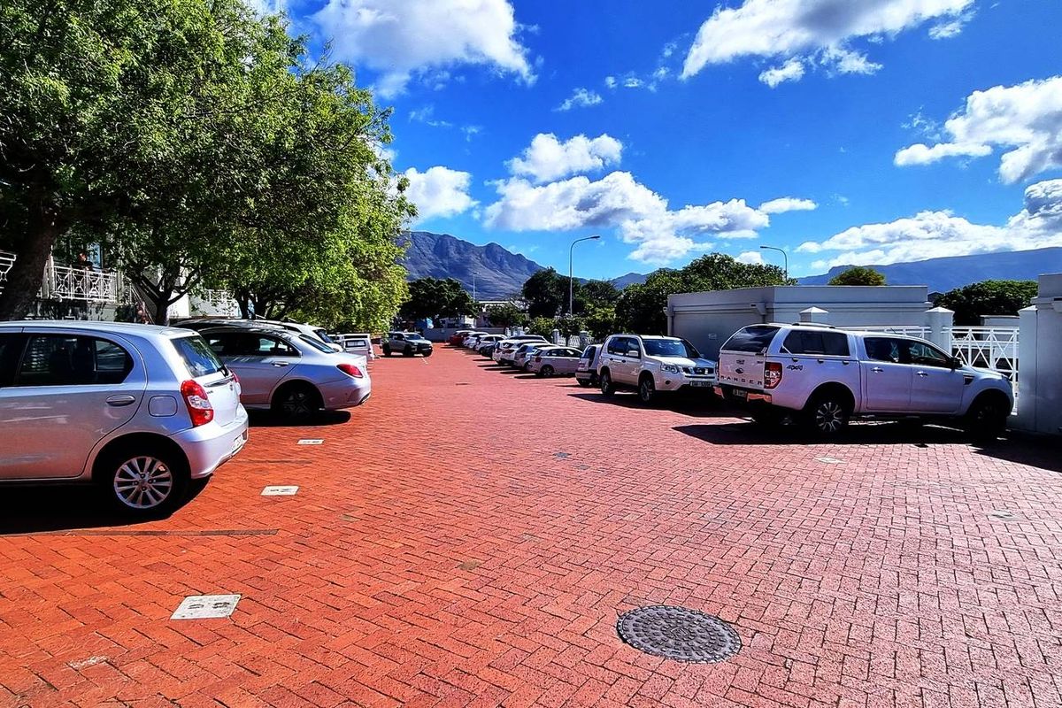 An outdoor paved parking area for the office property, featuring marked bays and mountain views in the background.