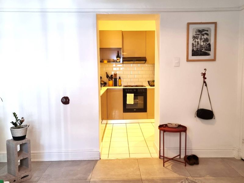 A compact kitchen featuring built-in cabinetry, a subway tile backsplash, and integrated cooking appliances, viewed from an adjacent living area.
