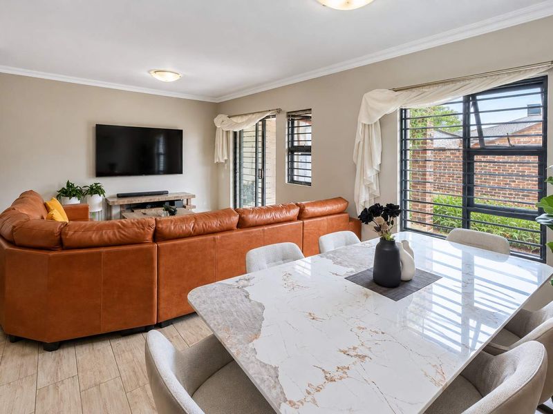 Spacious open-plan living and dining area featuring tiled flooring, modern finishes, and large windows with security bars for added peace of mind.