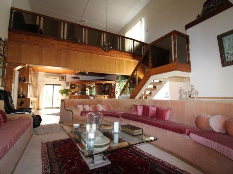 Spacious living room featuring a large built-in seating area, a wooden staircase leading to a mezzanine level, and an integrated bar area.