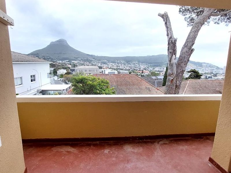 A covered balcony featuring a concrete floor and a clear view of the surrounding neighborhood and mountain landscape.