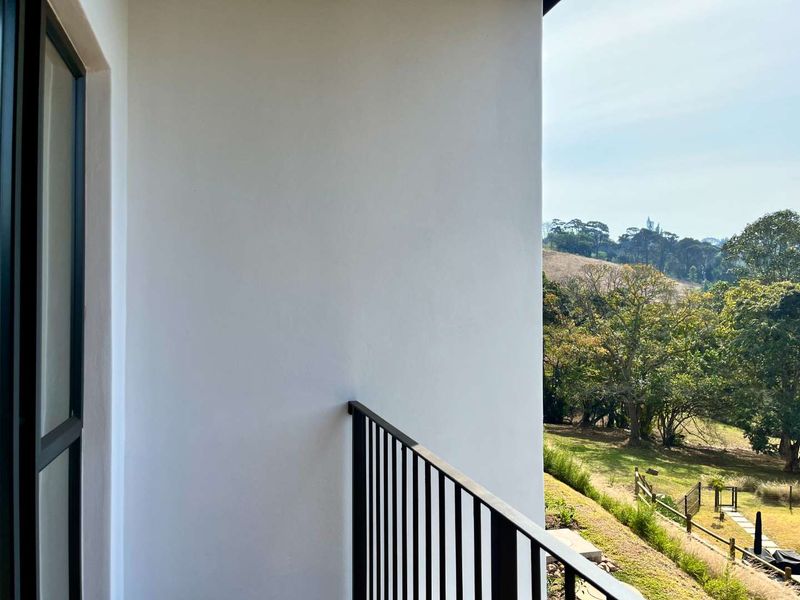 A clean, modern balcony featuring a sleek metal balustrade and offering scenic views of the surrounding landscape.