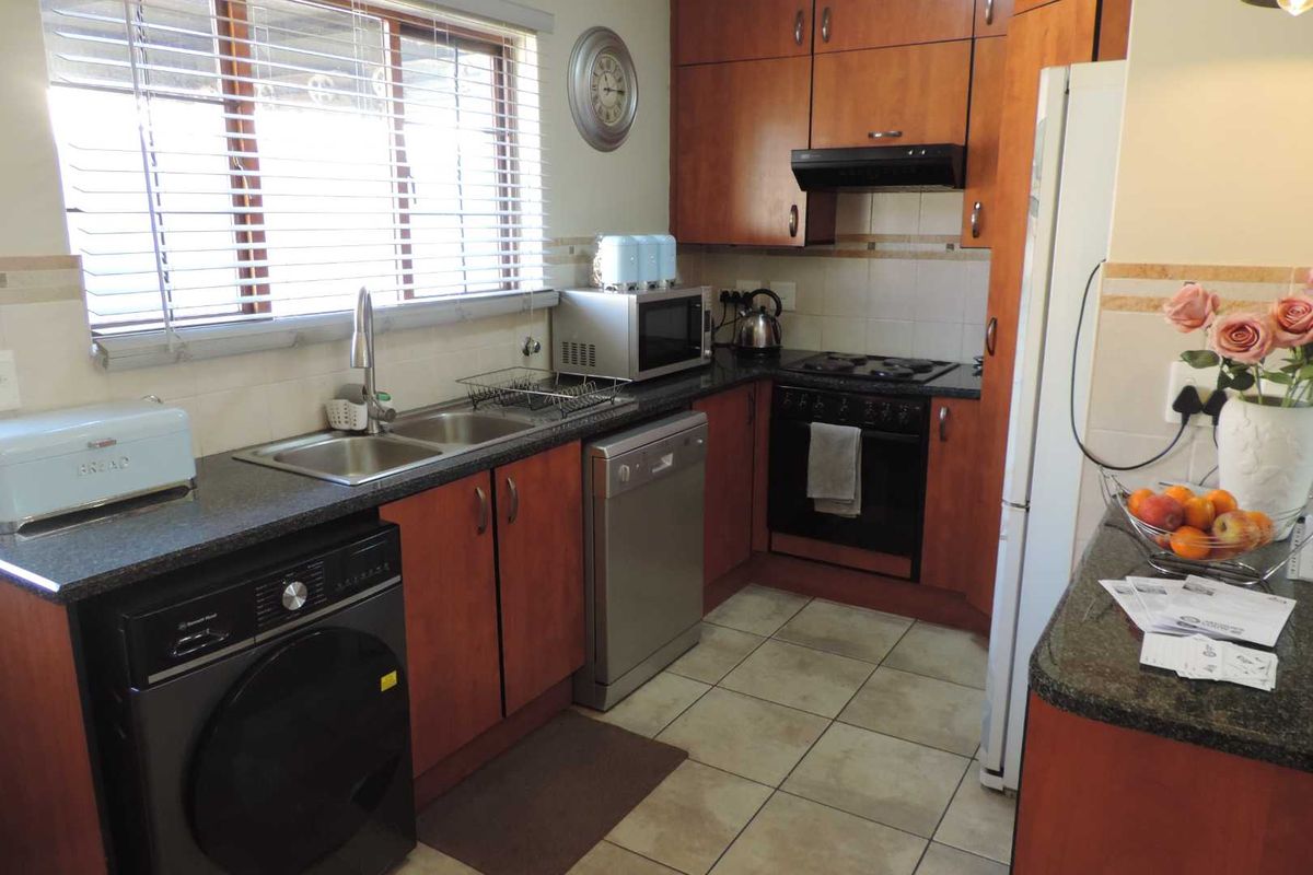 A functional kitchen featuring wood-finish cabinetry, granite countertops, integrated appliances, and tiled flooring, offering a practical layout for daily meal preparation.