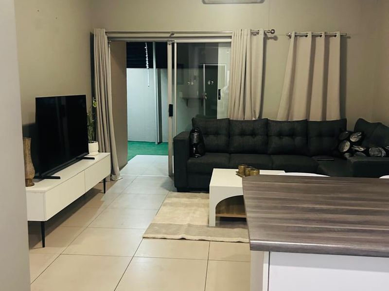 Open-plan living area featuring tiled flooring, a split-system air conditioner, and a sliding glass door leading to an outdoor space.
