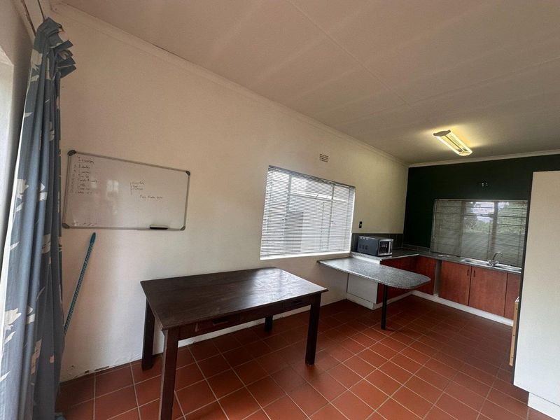 A functional kitchen area featuring tiled flooring, built-in cabinetry with laminate countertops, and a stainless steel sink, offering potential for modern updates.