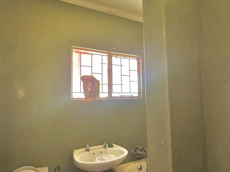A dated bathroom featuring a pedestal basin, toilet, and bathtub, with visible wear to the wall finishes and paintwork.