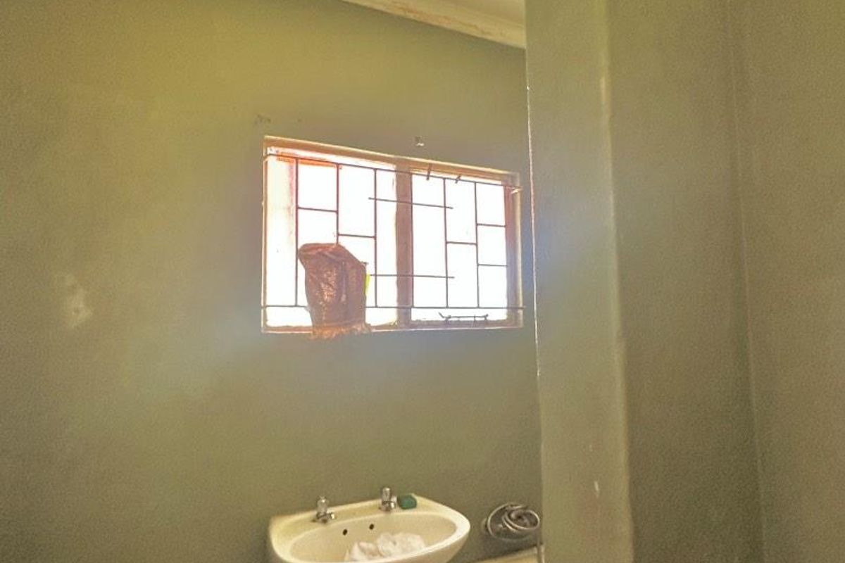 A dated bathroom featuring a pedestal basin, toilet, and bathtub, with visible wear to the wall finishes and paintwork.