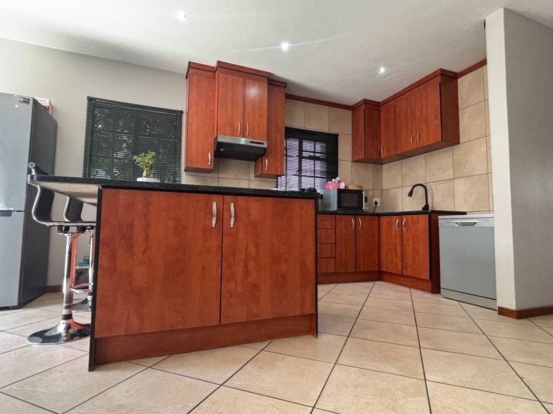 A well-maintained kitchen featuring cherry wood cabinetry, granite countertops, tiled backsplash, and recessed lighting, offering a functional and classic design.