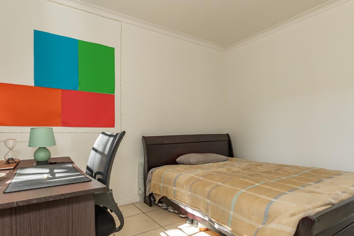 A functional bedroom featuring tiled flooring and neutral walls, suitable for a guest room or home office setup.
