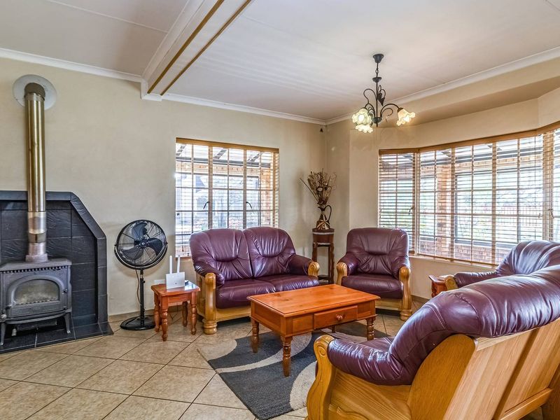 A comfortable living room featuring a cast iron wood burning stove, tiled flooring, and a large bay window providing natural light.