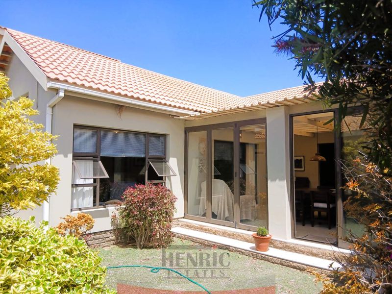 Rear view of the property featuring terracotta roof tiles, aluminium framed windows, and sliding doors leading to a small garden area.