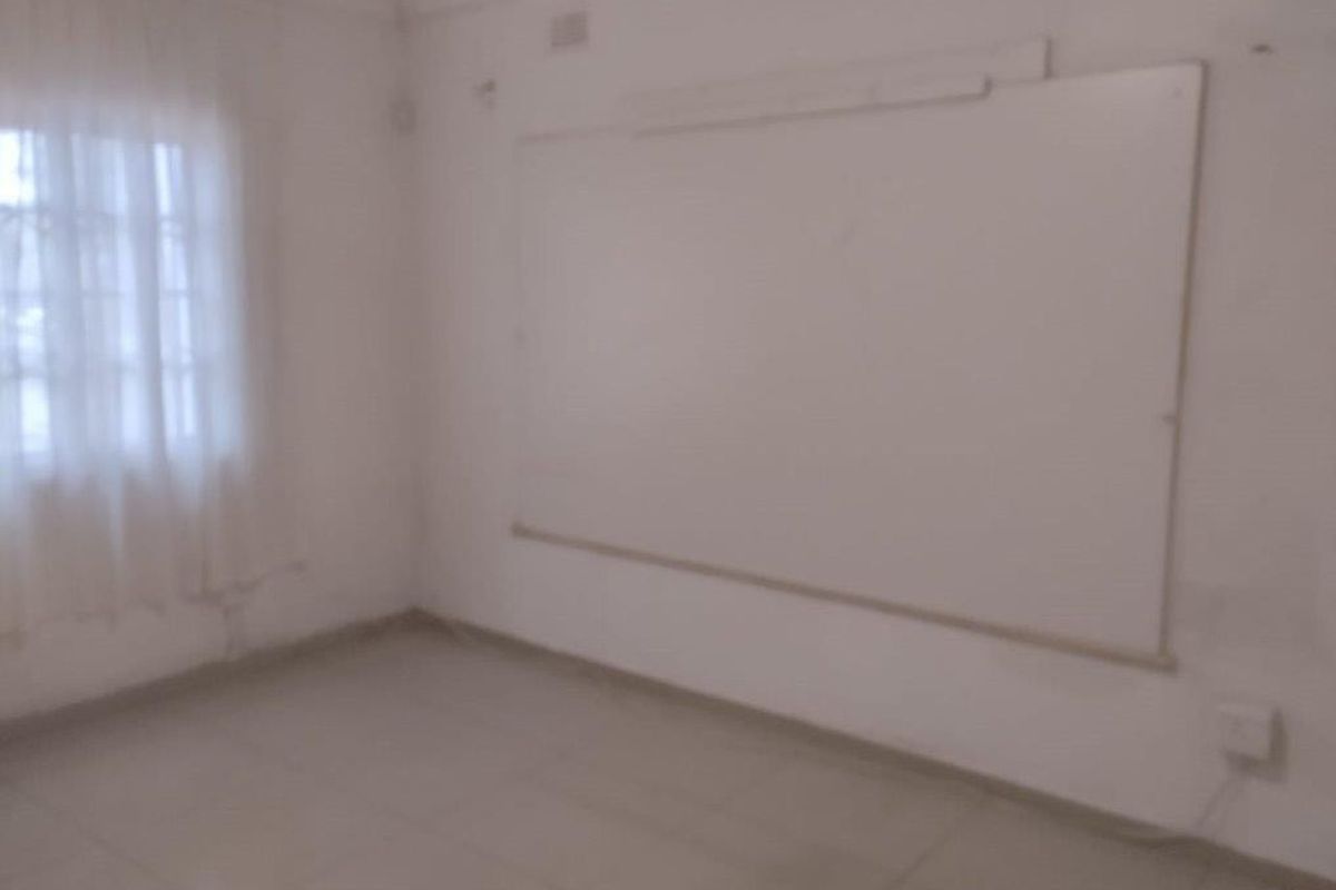 An empty bedroom featuring tiled flooring and a wall-mounted whiteboard, requiring cosmetic updates to improve its overall appeal.
