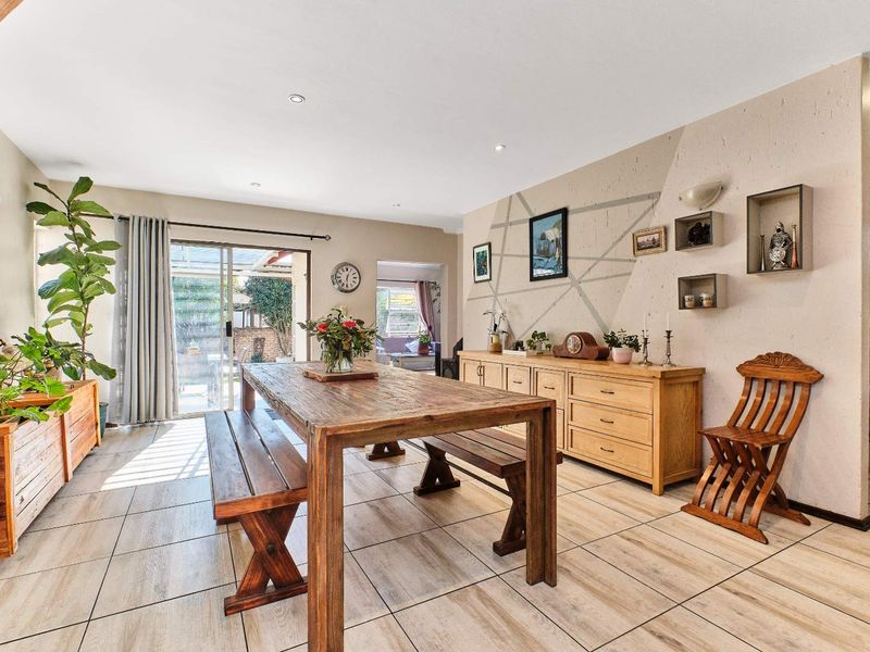 Spacious dining area featuring light-toned tiled flooring, recessed lighting, and a sliding glass door providing direct access to the outdoor patio.