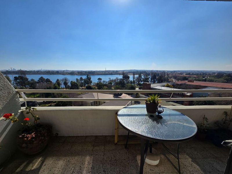 A balcony featuring a metal balustrade and tiled flooring, offering expansive views over the surrounding landscape and lake.