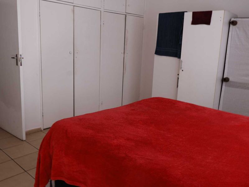 A bedroom featuring built-in cupboards and tiled flooring, offering a functional space with neutral finishes.