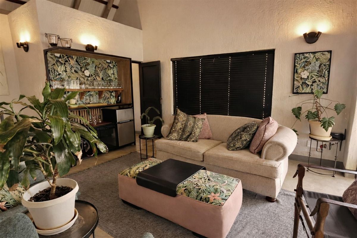A cozy living room featuring high vaulted ceilings, integrated bar cabinetry, and dark window blinds, creating a warm and inviting atmosphere.