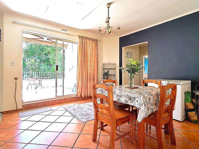 Dining area featuring terracotta floor tiles, coved ceilings, and a sliding glass door providing access to an outdoor patio space.