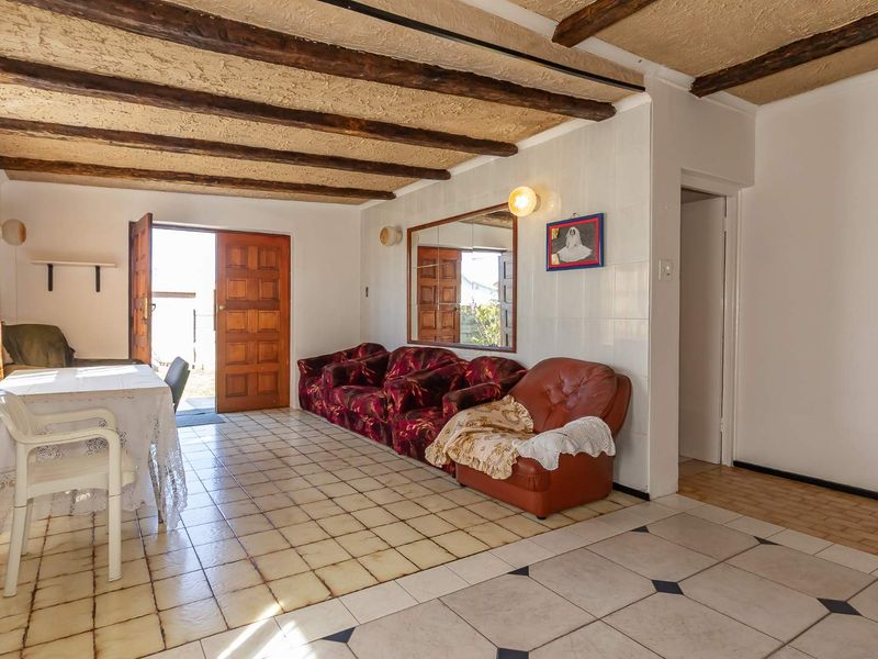 Living area featuring exposed timber ceiling beams, tiled flooring, and direct access to the exterior through a timber door.