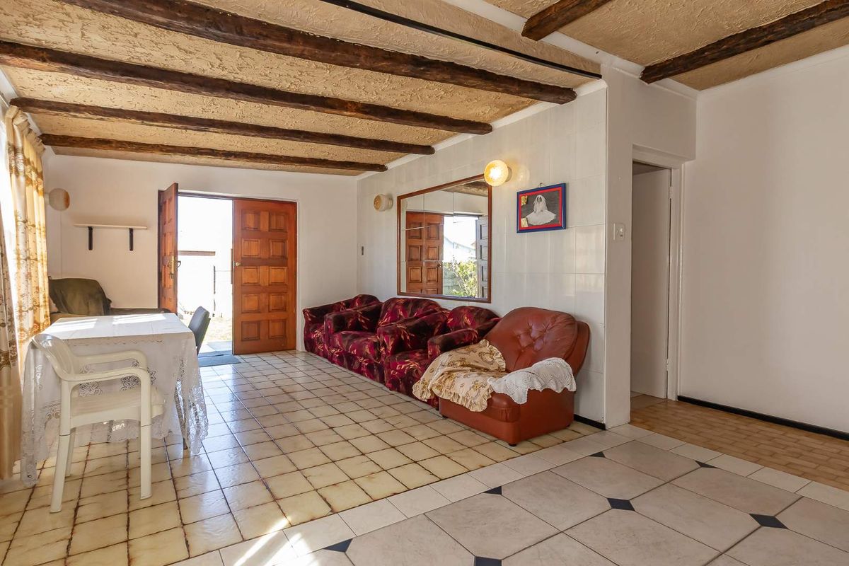 Living area featuring exposed timber ceiling beams, tiled flooring, and direct access to the exterior through a timber door.