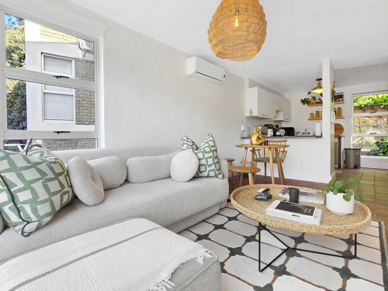 Bright open-plan living and kitchen area featuring tiled flooring, split-system air conditioning, and large windows providing natural light.