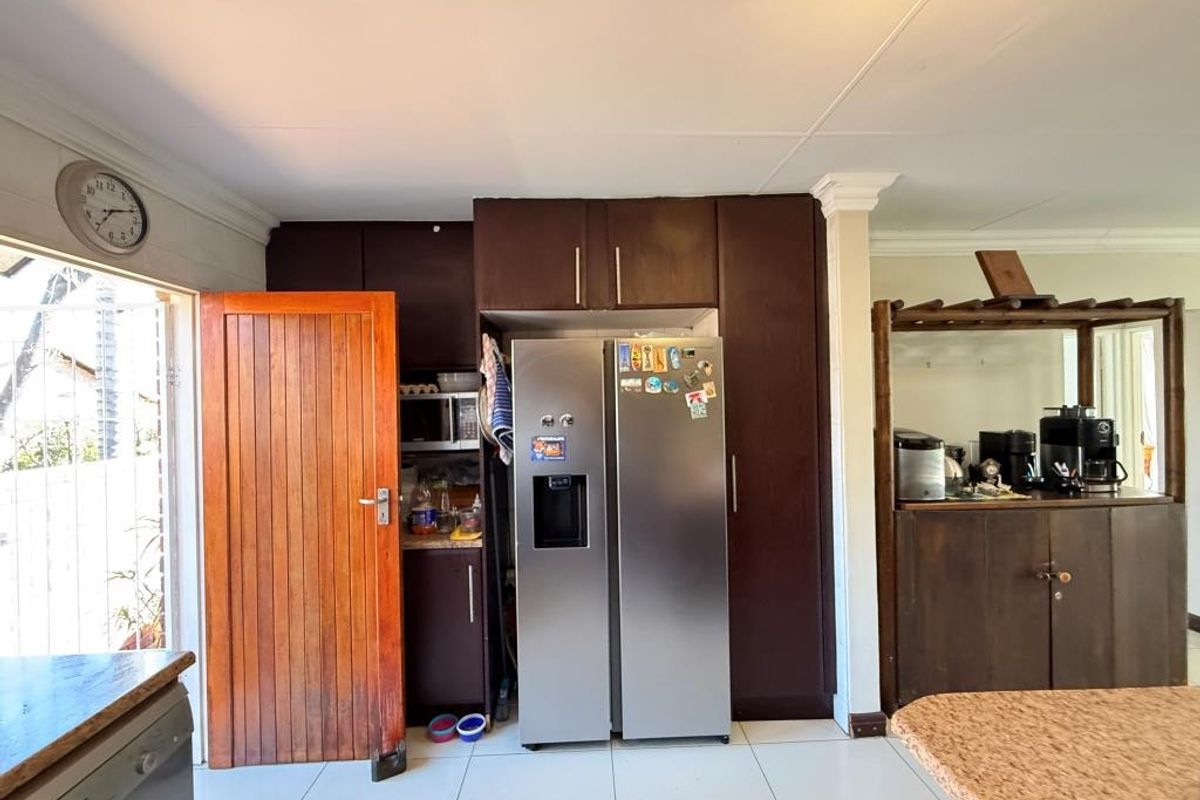 Kitchen area featuring dark wood cabinetry, tiled flooring, and a built-in pantry space, providing a functional layout for daily meal preparation.