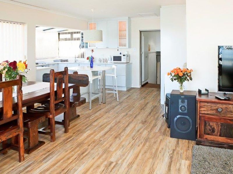 Open plan living and dining area featuring laminate flooring and a functional kitchen with island bench and cabinetry.