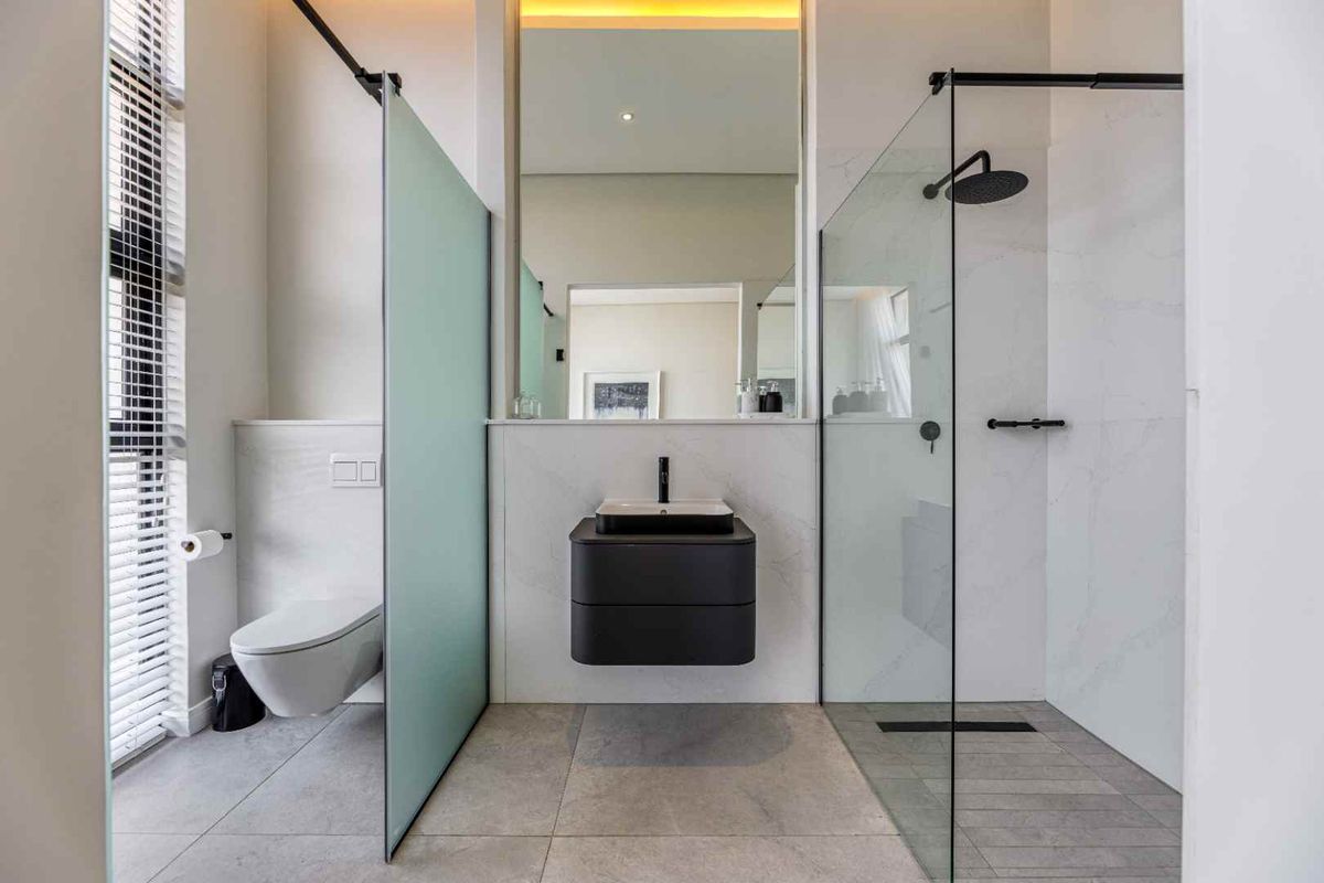Modern bathroom featuring a wall-mounted vanity, walk-in glass shower with rainfall showerhead, and a wall-hung toilet with concealed cistern.