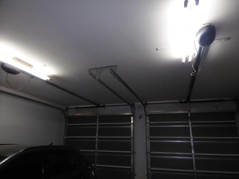 A spacious double garage featuring automated sectional doors and overhead lighting fixtures.