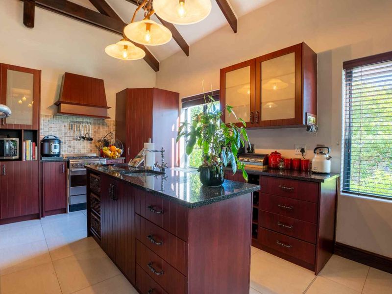 A well-appointed kitchen featuring dark wood cabinetry, granite countertops, a central island, and exposed timber beams, offering a warm and functional cooking space.