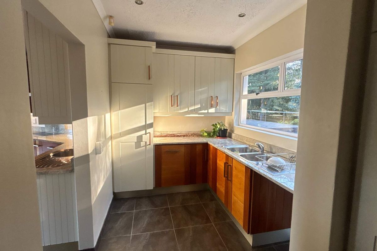 A functional kitchen featuring two-tone cabinetry, granite countertops, a double-basin sink, and recessed ceiling lighting, with a window providing natural light.