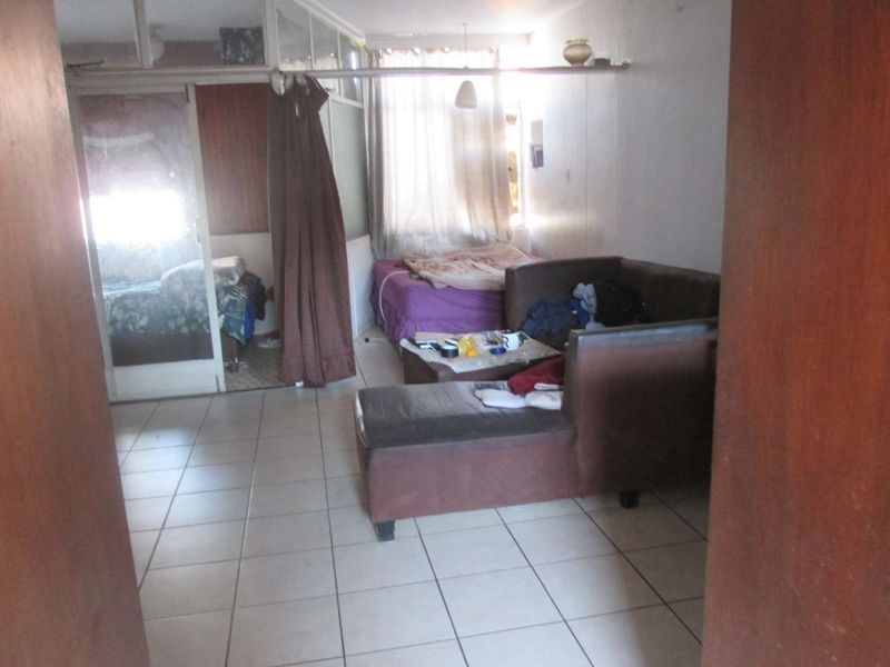 Open plan living area featuring tiled flooring and a glass partition wall, offering a flexible layout for various living arrangements.