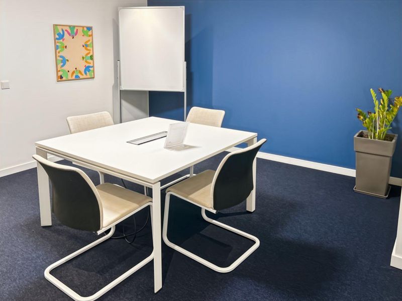 A modern office meeting room featuring dark blue accent wall, neutral carpeting, and clean, professional finishes suitable for collaborative work.