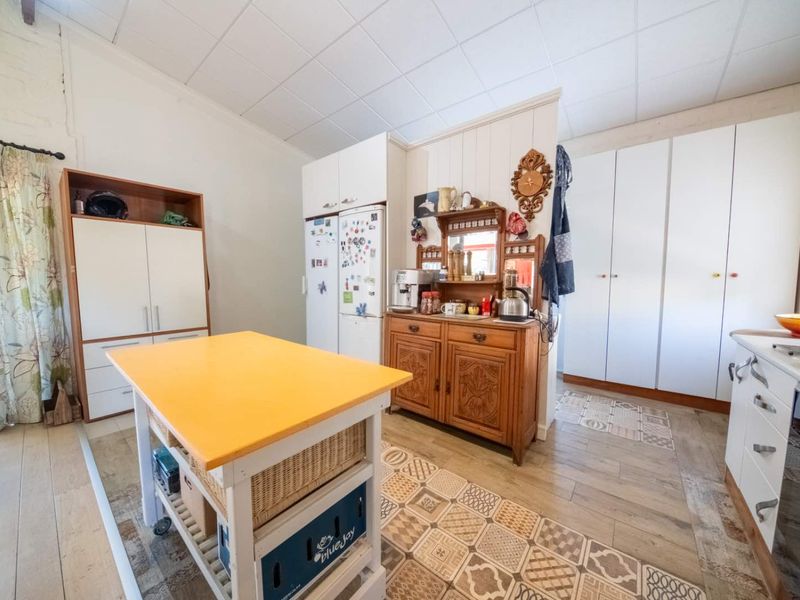 A functional kitchen space featuring built-in cabinetry, tiled flooring, and a drop ceiling, offering potential for a modern renovation.