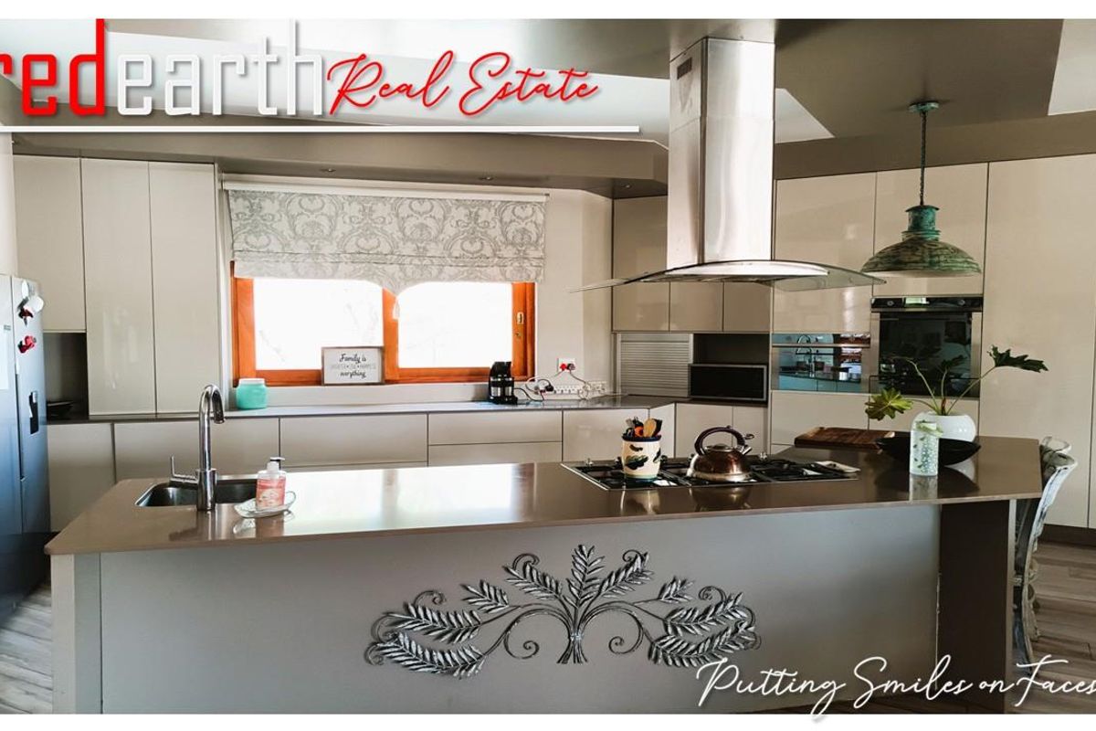 Modern kitchen featuring a central island with integrated gas hob, stainless steel extractor fan, sleek cabinetry, and ample counter space.