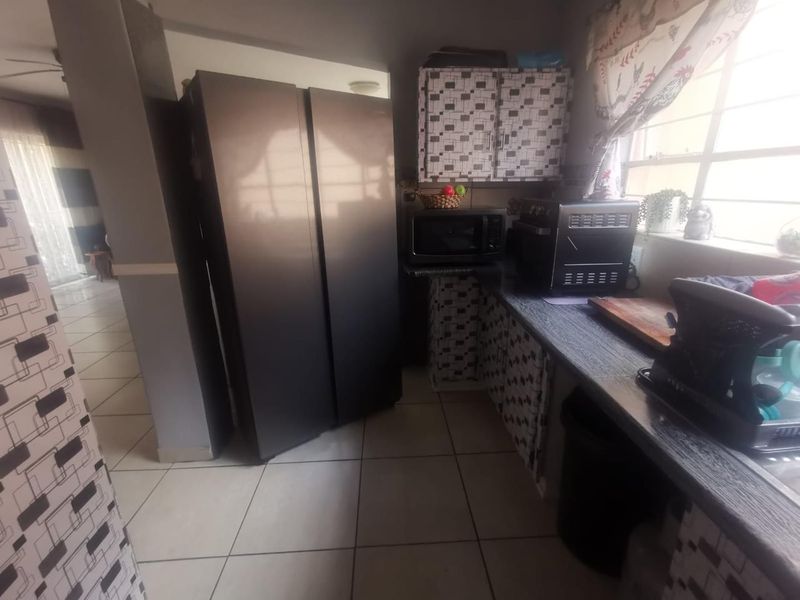 A functional kitchen area featuring tiled flooring, laminate countertops, and built-in cabinetry, offering a practical layout for daily meal preparation.
