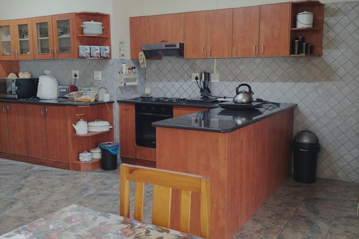 A functional kitchen featuring wooden cabinetry, dark countertops, a built-in oven, and a tiled backsplash, offering a practical layout for daily meal preparation.