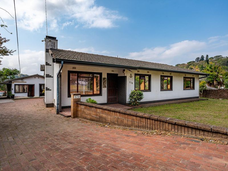 Front elevation of a single-story house featuring a tiled roof, brick driveway, and a low brick boundary wall.