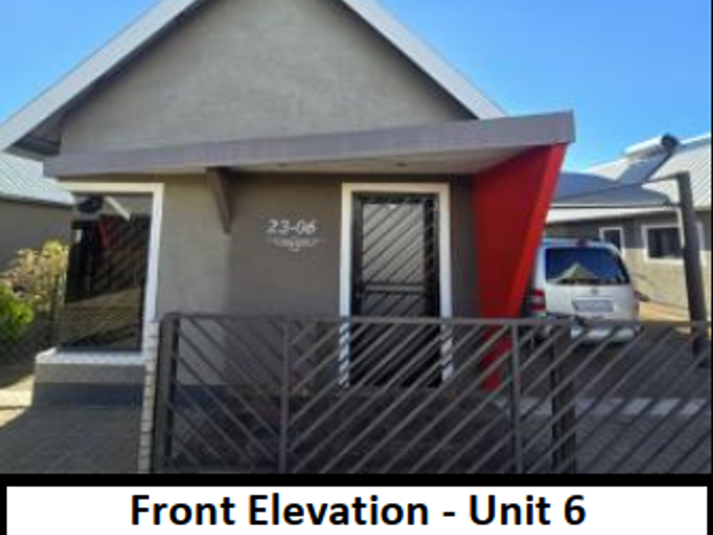 Front elevation of the property featuring a paved driveway, security gate, and entrance door with a modern red accent structure.