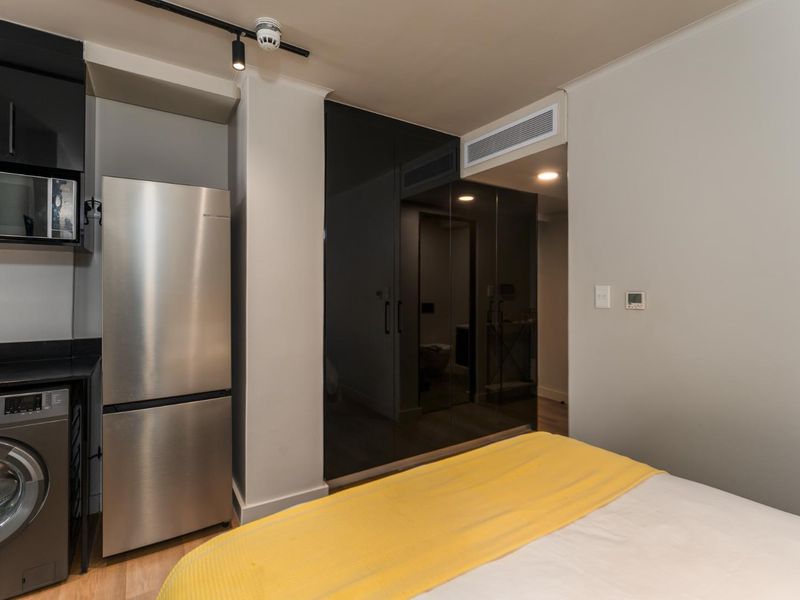 A modern bedroom featuring built-in high-gloss cabinetry, integrated microwave, and ducted air conditioning, offering a sleek and functional living space.