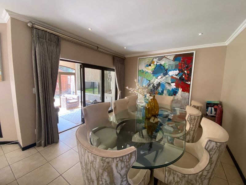 A well-lit dining room featuring tiled flooring, crown molding, and large sliding glass doors that provide direct access to the outdoor patio area.