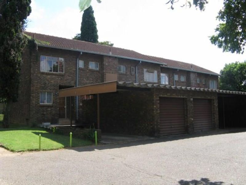 Front exterior view of a multi-story apartment complex featuring face brick construction, tiled roofing, and integrated garage and carport parking facilities.