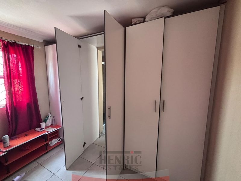A bedroom featuring built-in cupboards and tiled flooring, providing functional storage space within the townhouse.