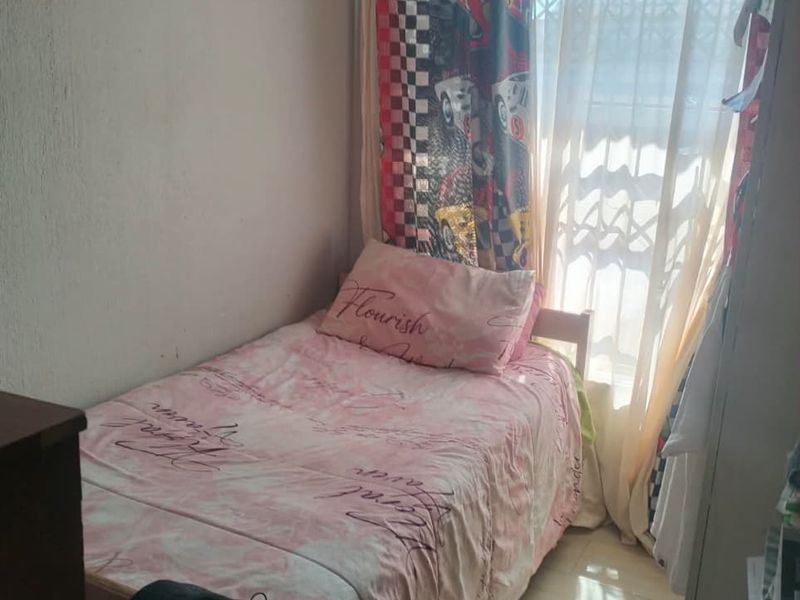 A compact bedroom featuring tiled flooring and a window fitted with a security gate, providing natural light.