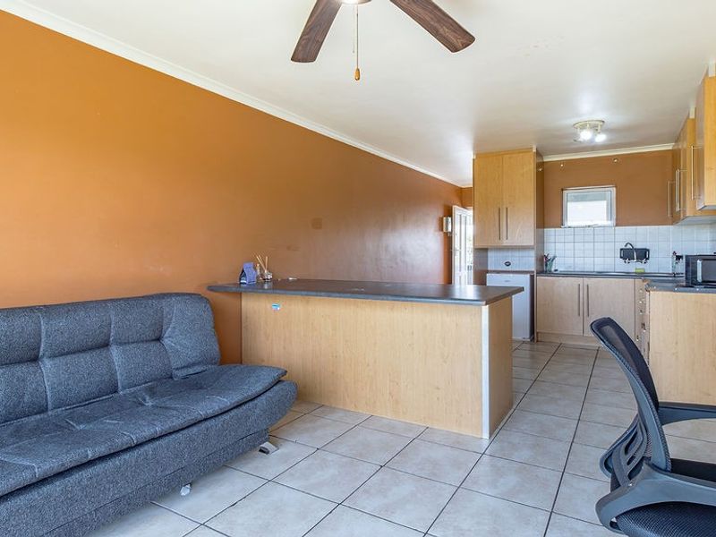 Open plan living area featuring a kitchen with breakfast bar, tiled flooring, and ceiling fan, offering a functional layout for modern apartment living.
